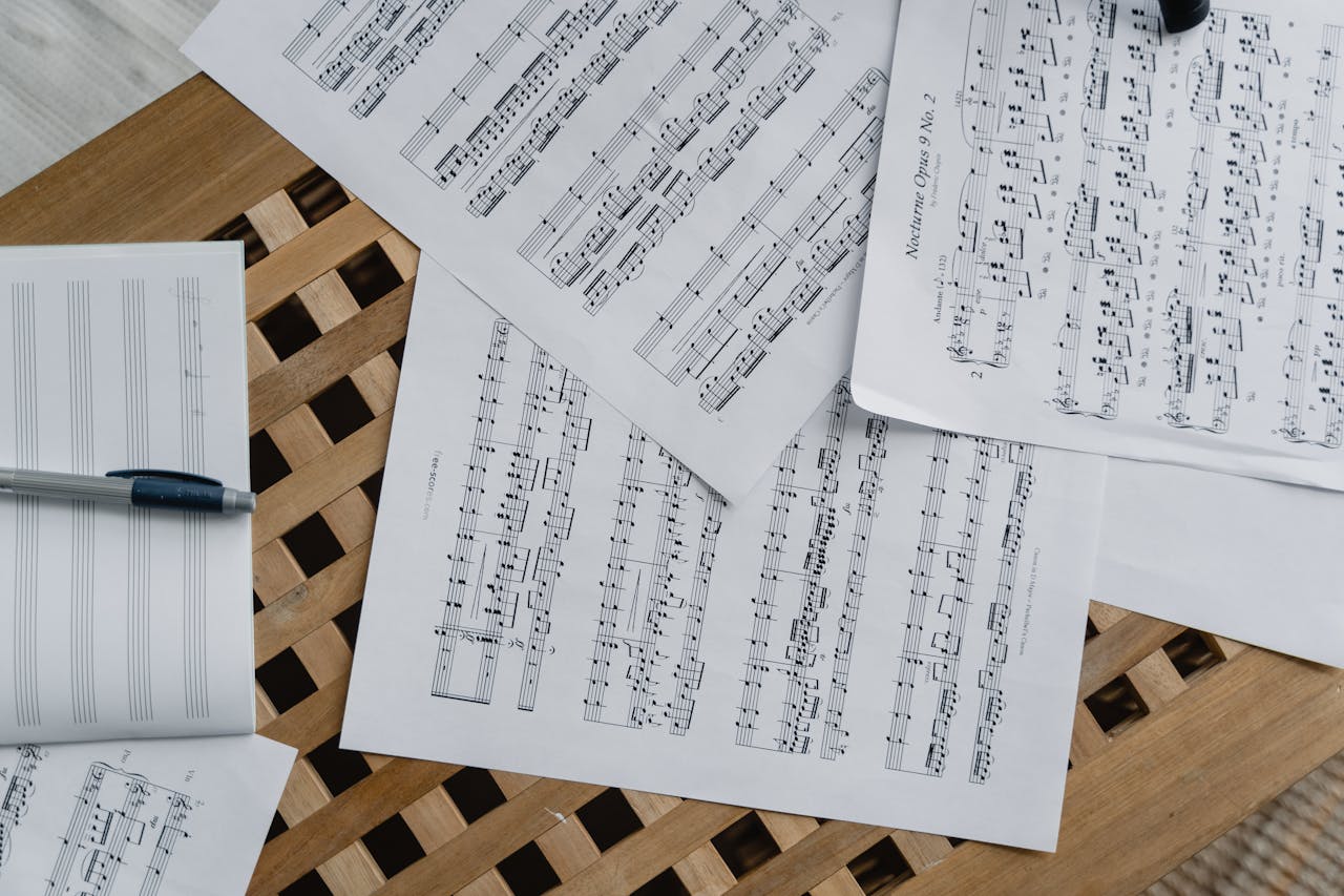 Top view of classical sheet music and a pen on a wooden surface. Perfect for composers.
